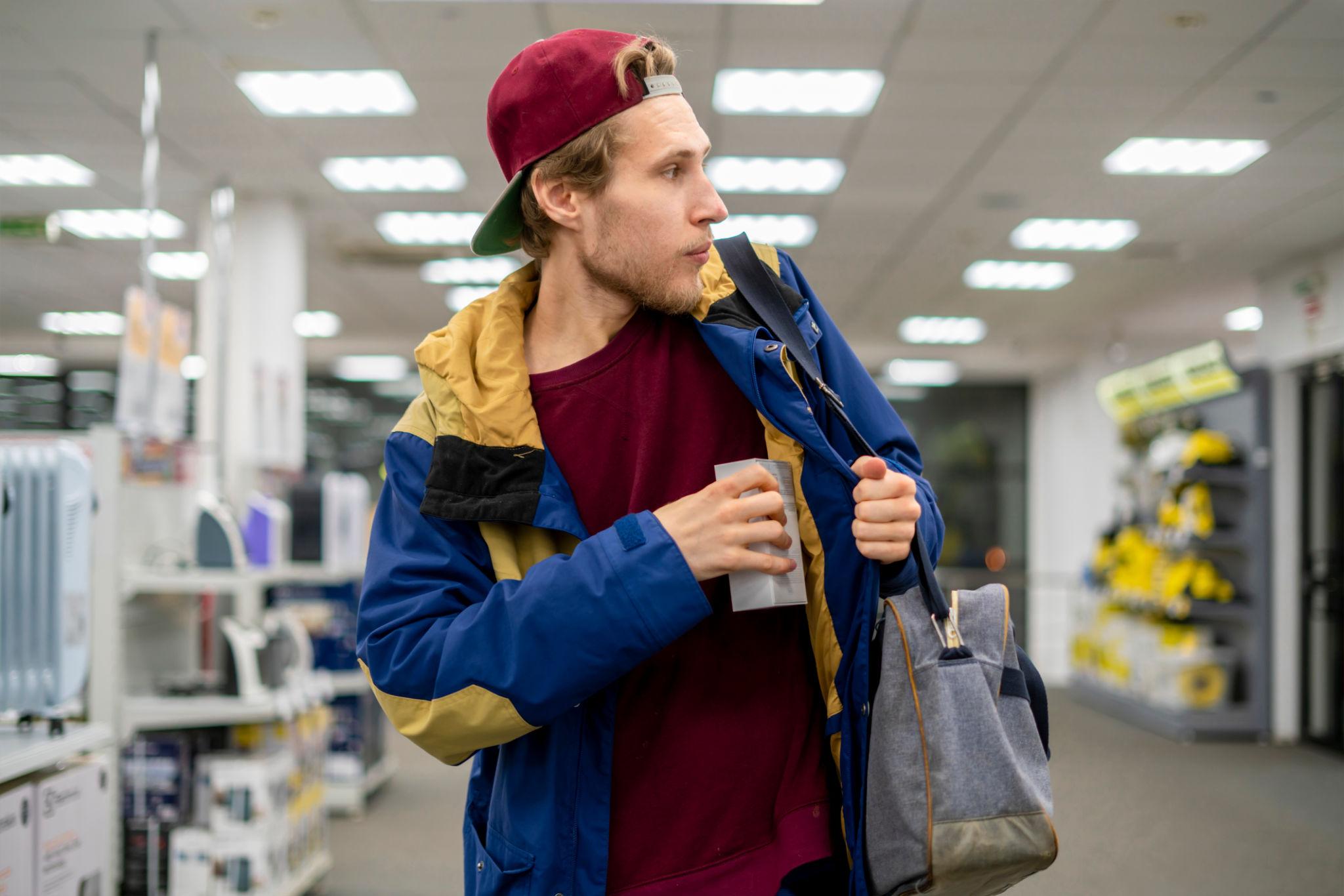 un voleur à l'étalage dans le rayon électronique d'un supermarché en train de voler un gadget neuf 