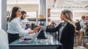 Un vendeur traitant le retour d'un client au comptoir de la caisse, ce qui illustre l'importance des procédures de vérification des retours pour prévenir les retours frauduleux et les pertes de stock.