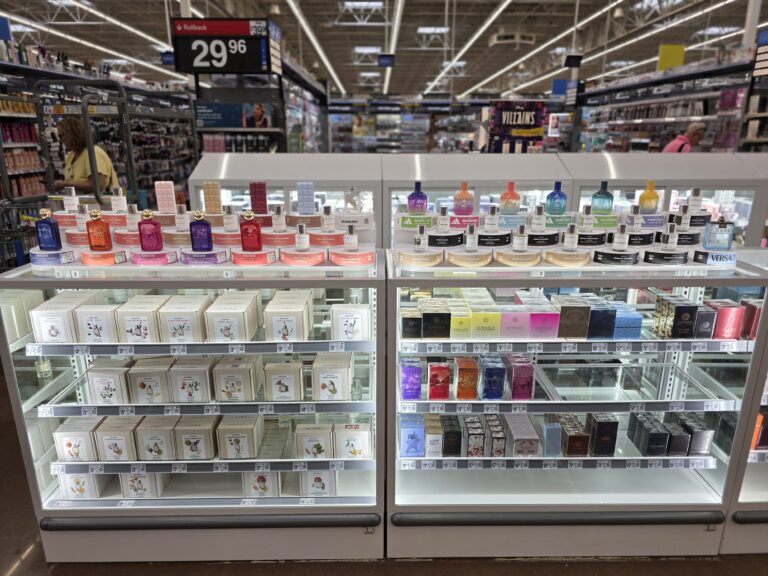 une vitrine en verre contenant le stock de coffrets de parfum, surmontée de présentoirs de testeurs permettant au client de découvrir les parfums.