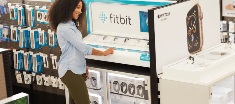 Femme devant le présentoir Fitbit dans un magasin de détail