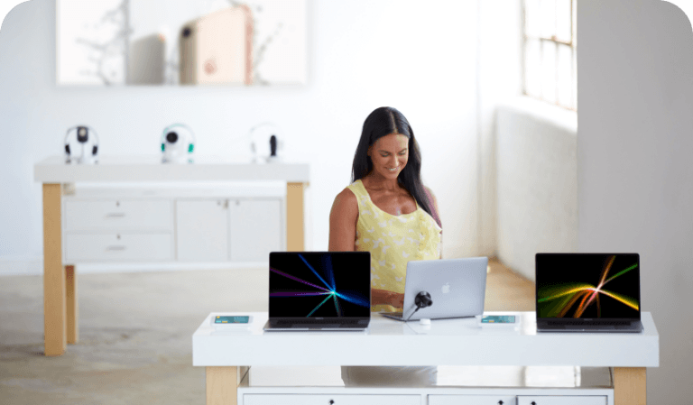 Femme regardant des ordinateurs portables sur une table dans un magasin de téléphonie mobile