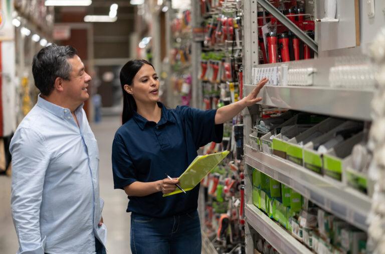 Homme faisant ses courses dans un magasin de bricolage et discutant avec une vendeuse