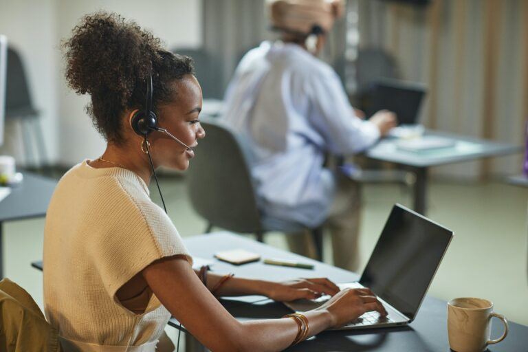 Femme assise devant un ordinateur portable avec un casque de service à la clientèle