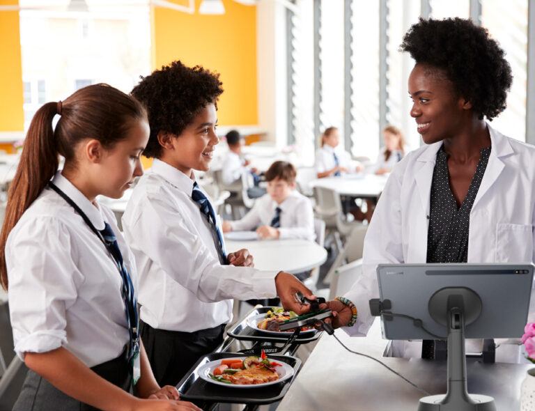 Employé d'école devant le stand de tablettes NE150 avec deux élèves en uniforme