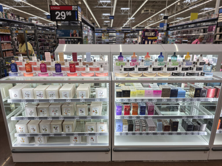 une vitrine en verre contenant le stock de coffrets de parfum, surmontée de présentoirs de testeurs permettant au client de découvrir les parfums.